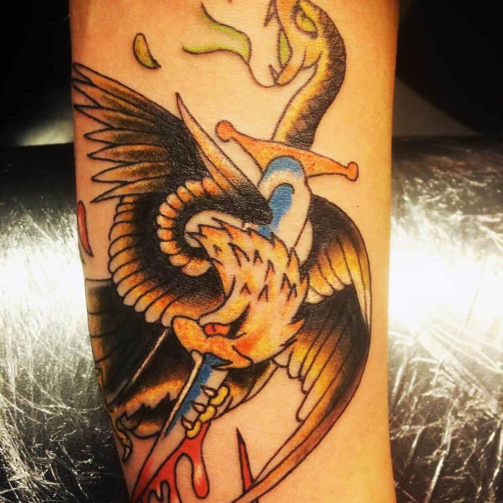Tattoo of an eagle wrapped around a dagger with a snakes-head hilt. John at Rogsy Tattoo Studio.