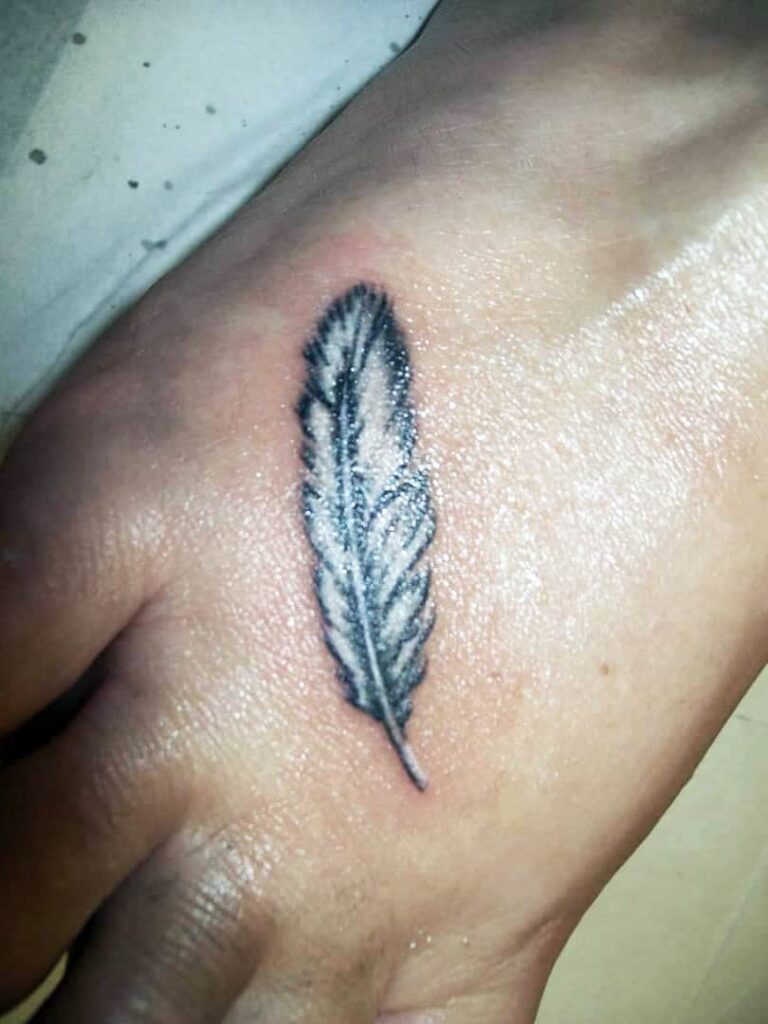 Tattoo of a white feather. On foot. John at Rogsy Tattoo Studio.